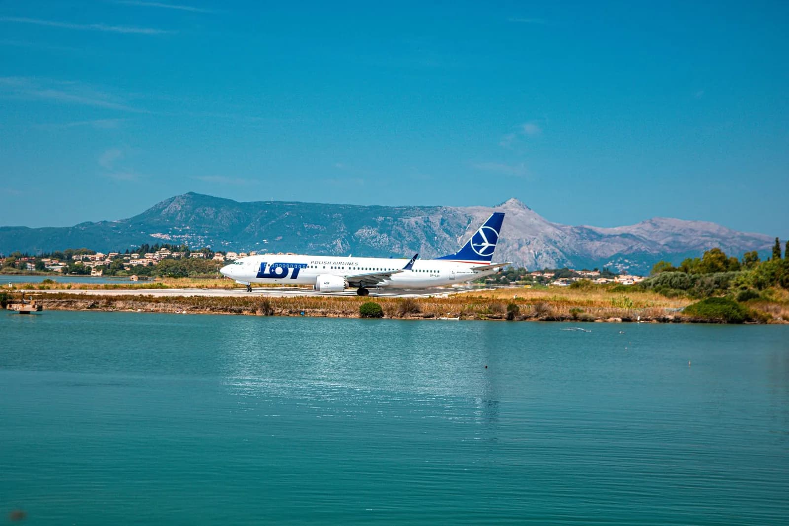 An airliner on the runway of Corfu airport, with the lagoon in front and the island's mountains behind