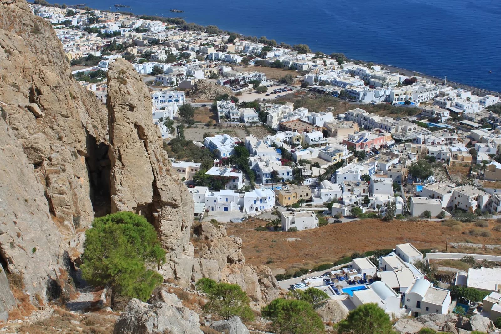 The east coast of Santorini seen from the slope of Mesa Vouno, Kamari spread along its black sand beach on the flat ground the airport shares