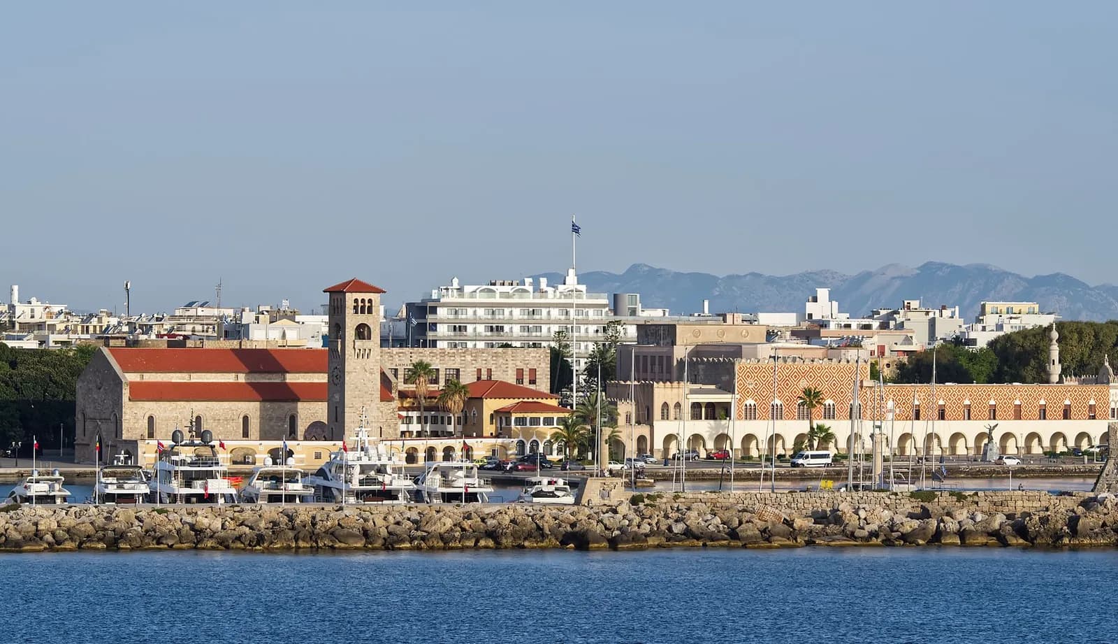 The Mandraki waterfront in Rhodes Town, with the church of Evangelismos, the Governor's Palace and the mountains of the Turkish coast behind