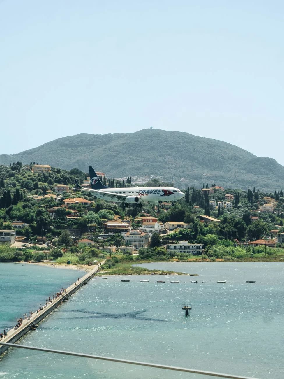An airliner on final approach to Corfu airport, passing low over the Kanoni causeway and lagoon