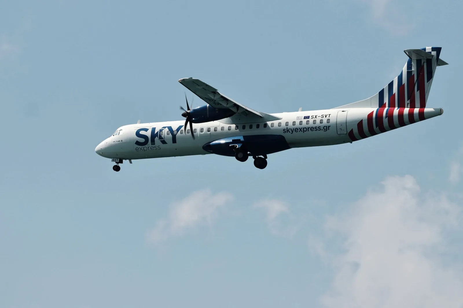 A Sky Express ATR 72 turboprop on approach with its landing gear down, the type of aircraft that flies between Athens and Paros