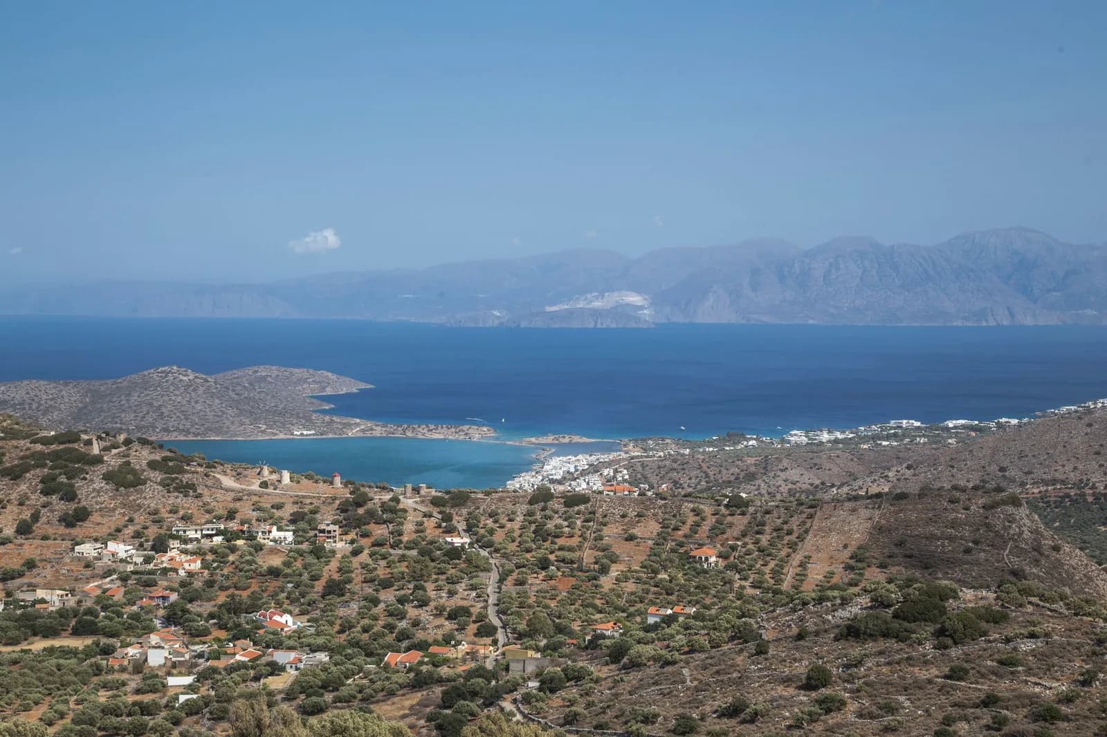 The Gulf of Mirabello in eastern Crete seen from the hills above Elounda, with the isthmus and its old windmills, olive terraces in the foreground and range after range of mountains across the water