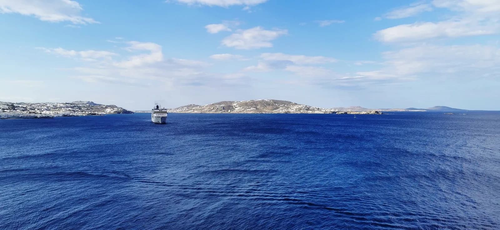 A ferry approaching Mykonos across the Aegean, with the whitewashed town spread along the shore