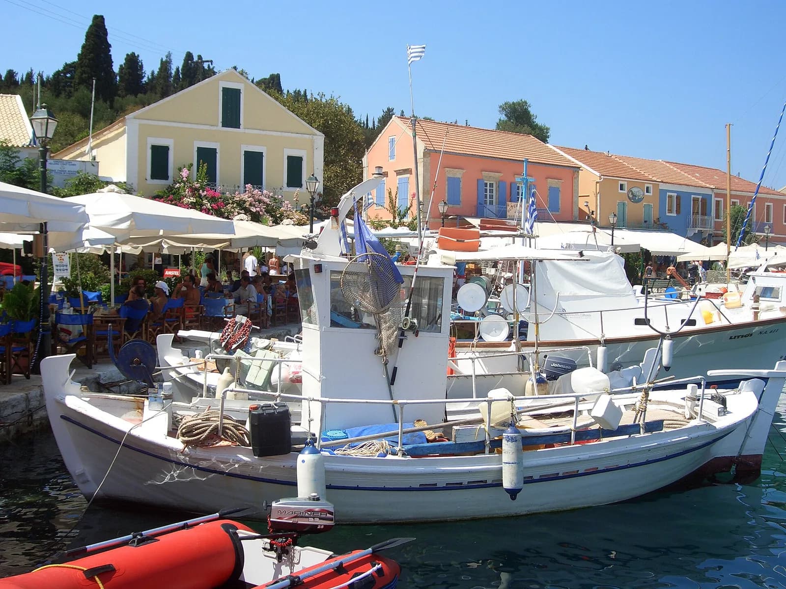 Fishing boat moored along the pastel Venetian-style waterfront houses of Fiskardo harbour, Kefalonia