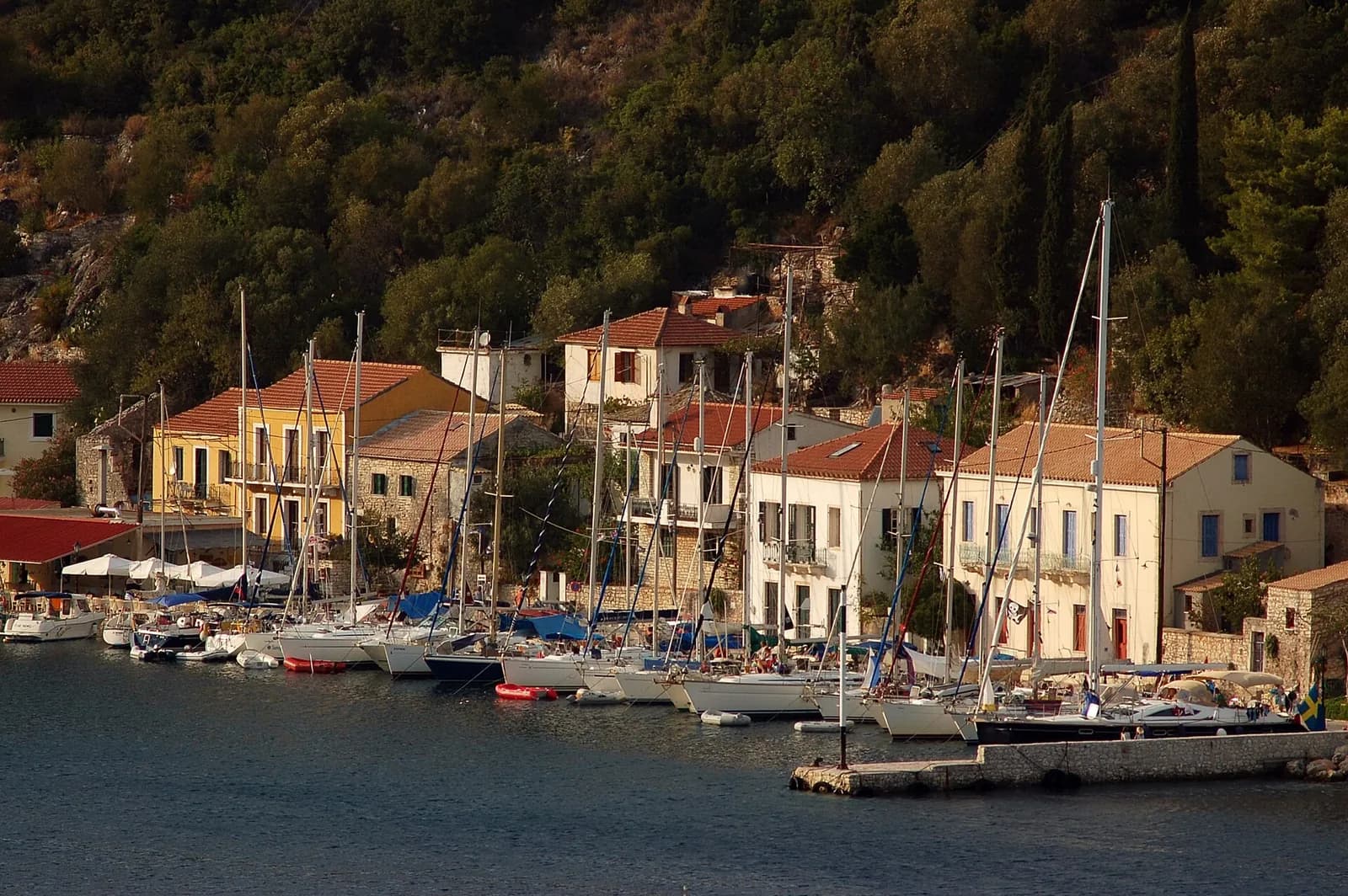 Stone mansions and moored sailing boats along the small harbour of Kioni, north Ithaca