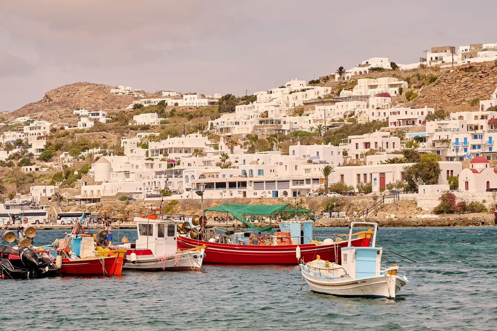 Fishing boats moored in the Old Port of Mykonos, with the white houses of Mykonos Town rising behind