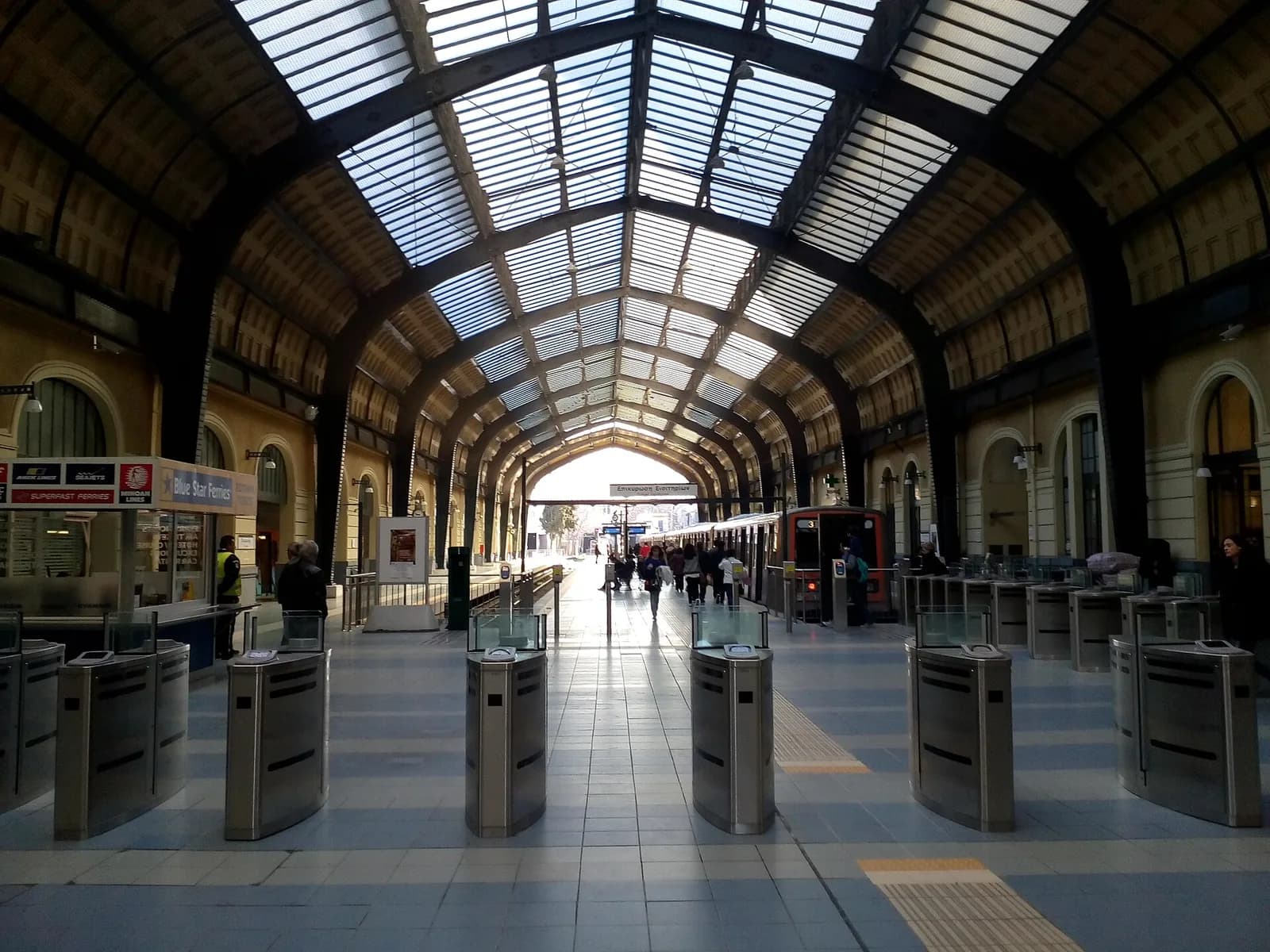 Glass-roofed concourse and ticket gates of Piraeus metro station, across the road from the ferry gates