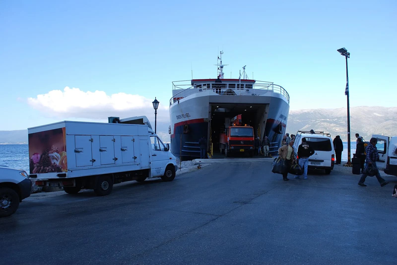 Ionion Pelagos ferry with its bow ramp open at the Piso Aetos quay on Ithaca, with a van and passengers on the pier