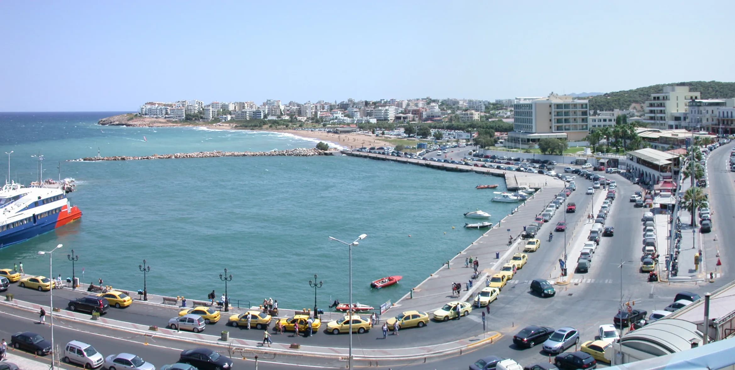 Panoramic view of Rafina harbor in Attica, Greece, with a ferry at the quay and the waterfront road curving along the bay
