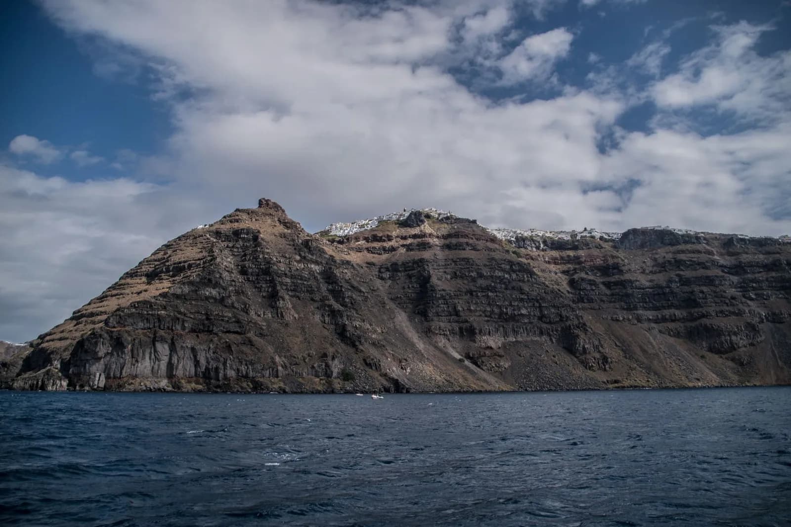 The caldera cliffs of Santorini seen from the water, with Fira strung along the top of the rock