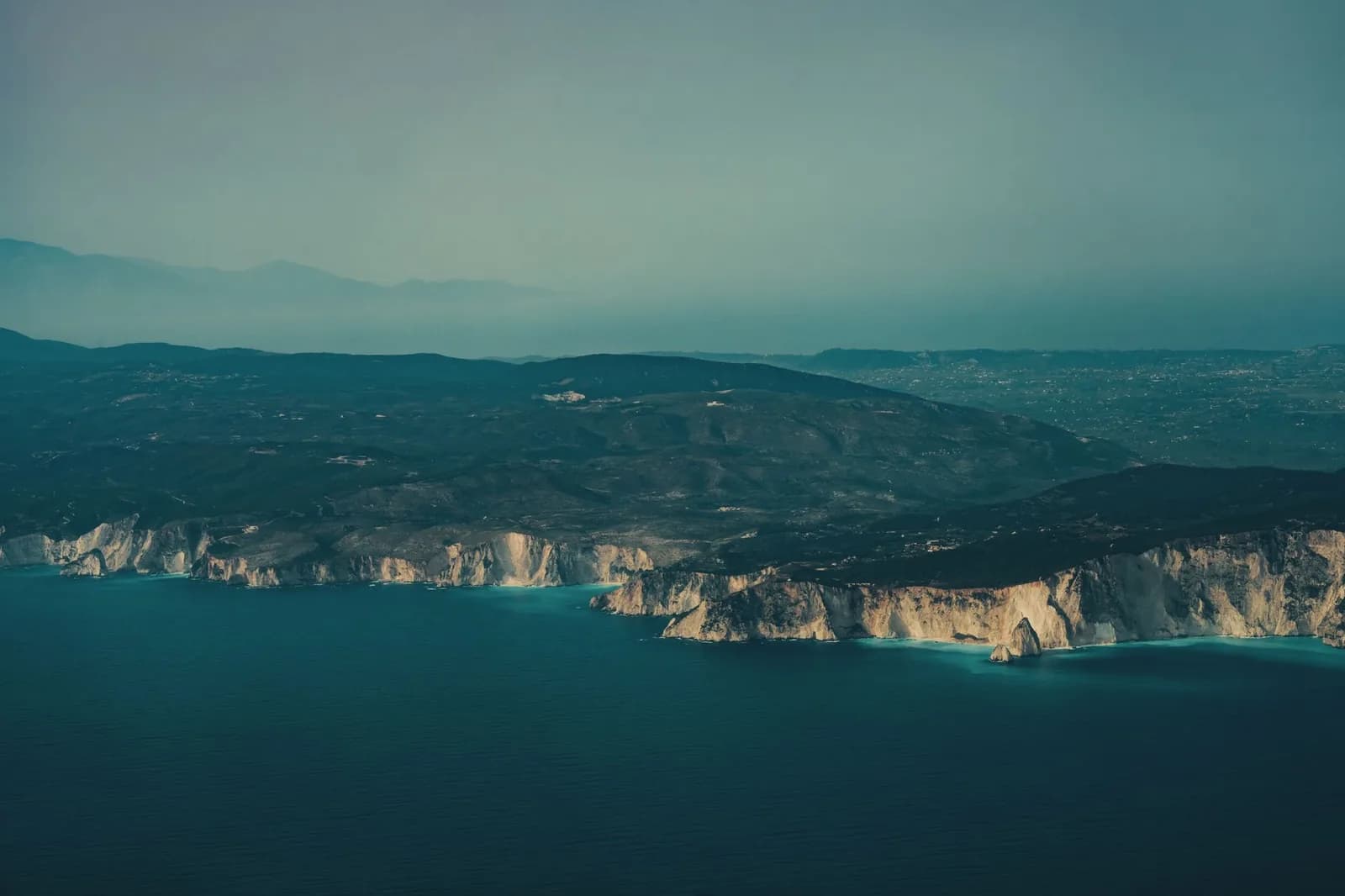 Limestone cliffs on the coast of a Greek island in the Ionian Sea, with a second island on the horizon