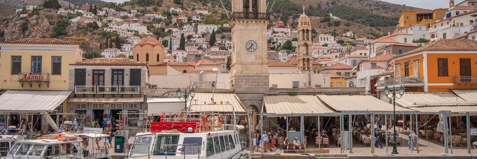 Hydra harbour front with the clock tower, cafés and stone mansions along the quay