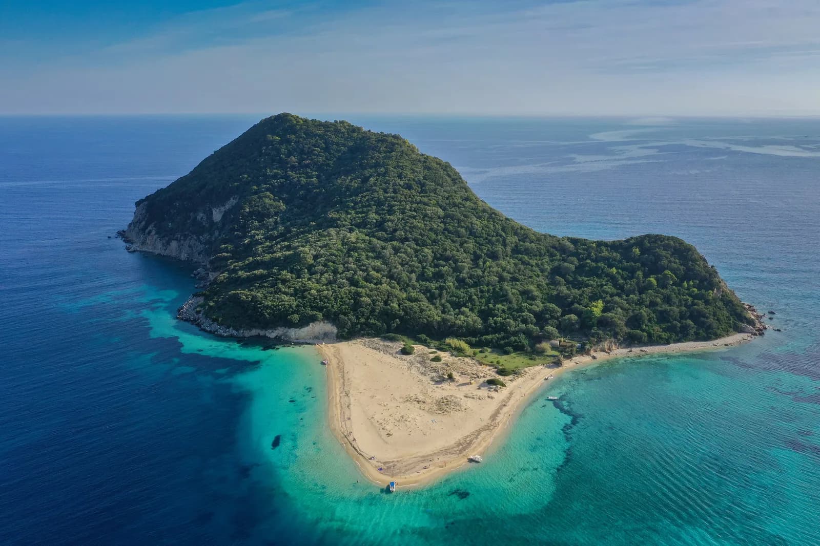 Aerial view of Marathonisi, the turtle-shaped islet in Laganas Bay off Keri, Zakynthos, a pine-covered hump with a pale sandy beach ringed by turquoise shallows