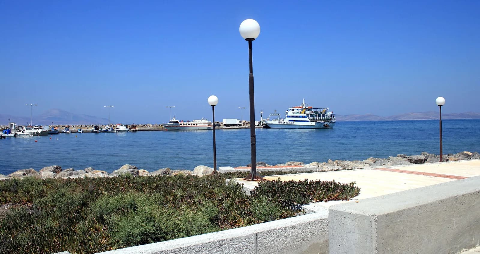The harbor at Mastichari on Kos, with a white ferry for Kalymnos at the quay and the mountains of Kalymnos across the water