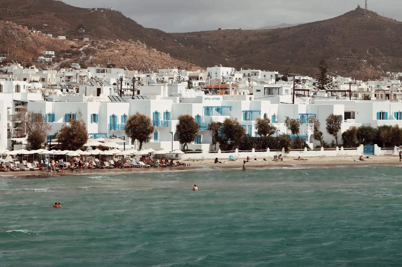 A row of whitewashed hotels on the beach at Agios Georgios, Naxos, with sunbeds on the sand