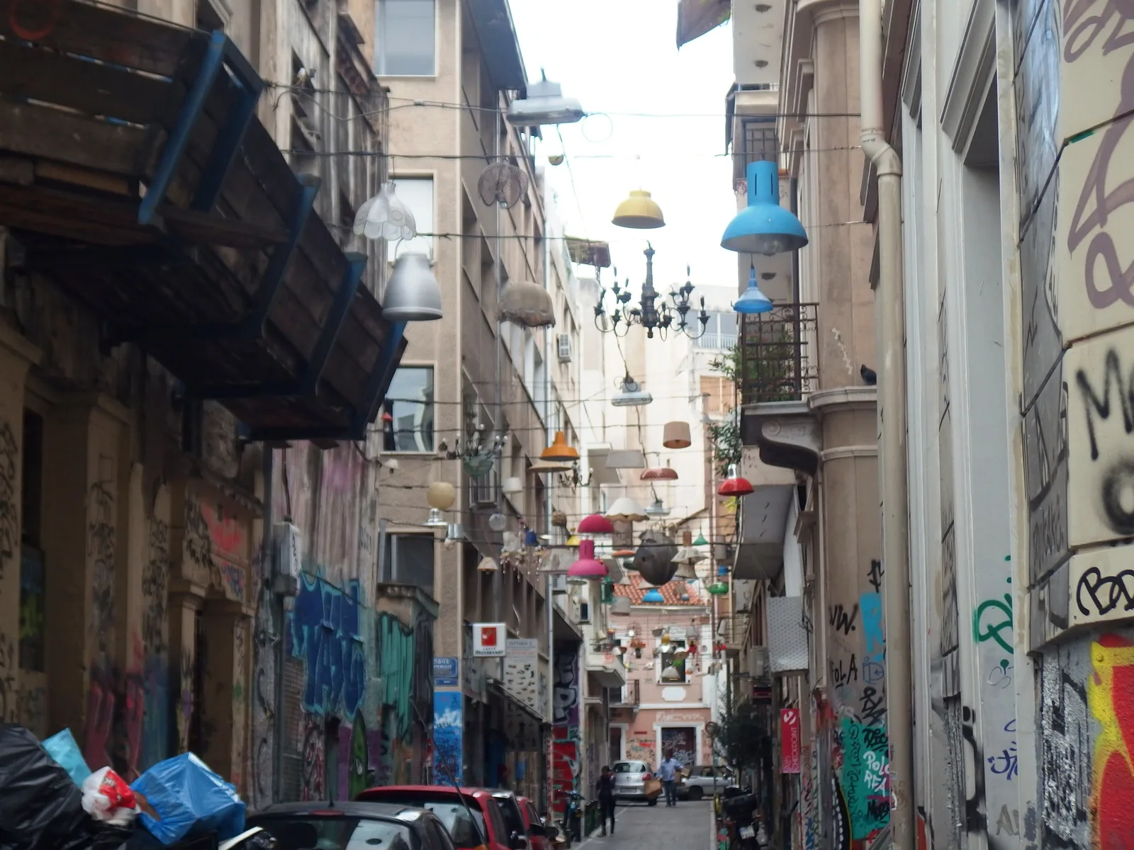 Pittaki Street in Psyrri, Athens, with graffiti-covered walls and colourful lamps hanging above the lane