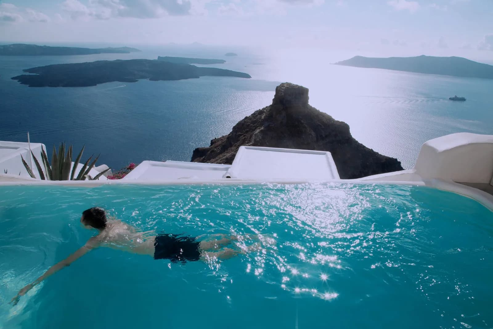 A private infinity pool on a hotel terrace at Imerovigli, Santorini, looking out over Skaros rock and the caldera towards the volcanic islets