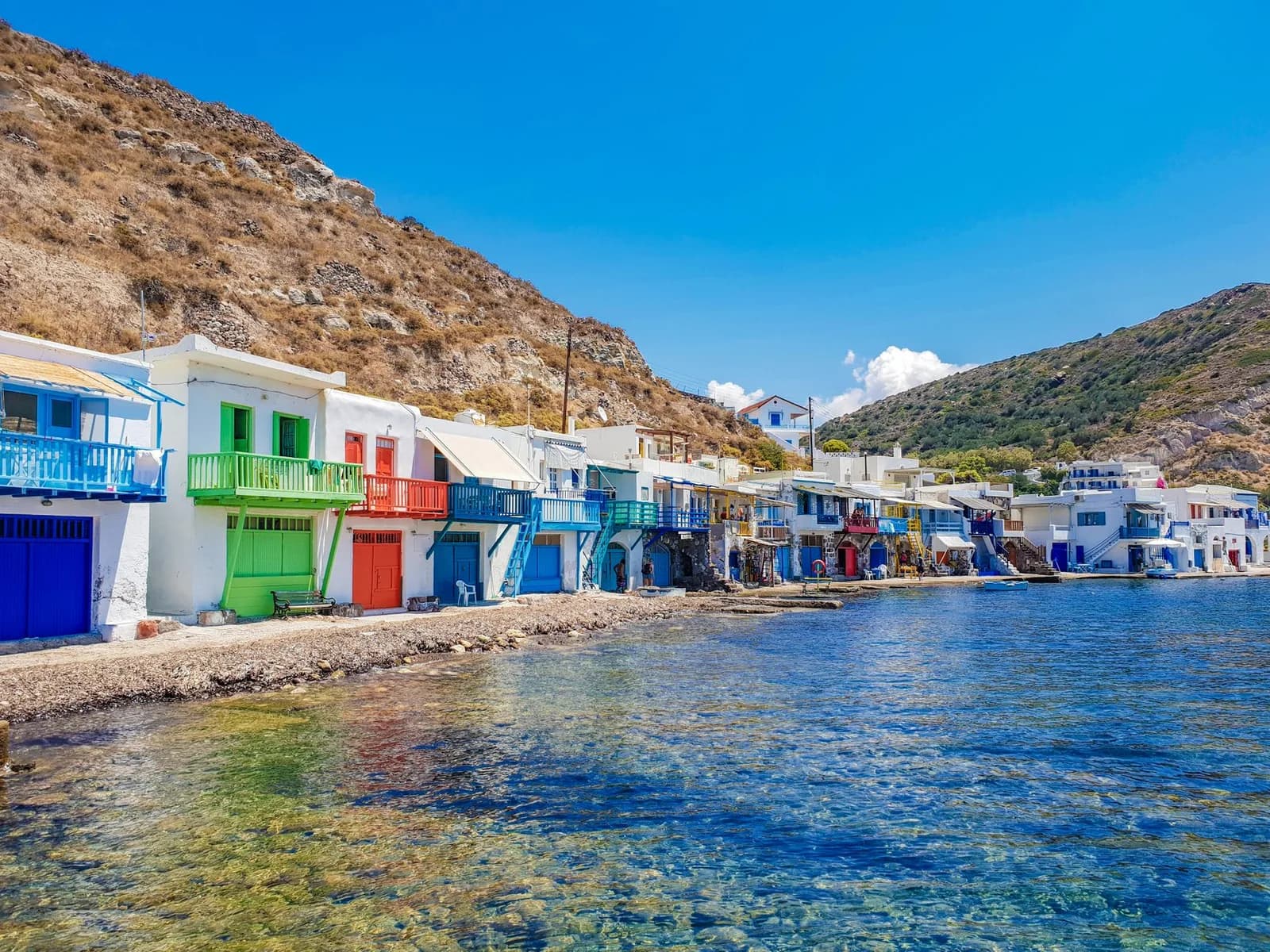 A row of syrmata on Milos, whitewashed boathouses with painted doors and balconies at the water's edge