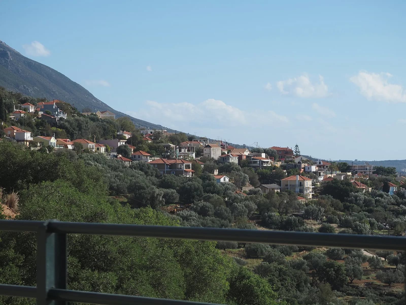 The hill village of Vlachata above Lourdas on the south coast of Kefalonia, red-roofed houses scattered through olive groves on a steep slope under the flank of Mount Ainos