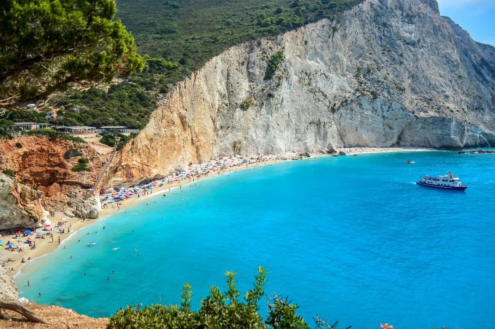 A wooded headland on the Ionian coast of Greece dropping in a white limestone cliff to a curved beach and turquoise water