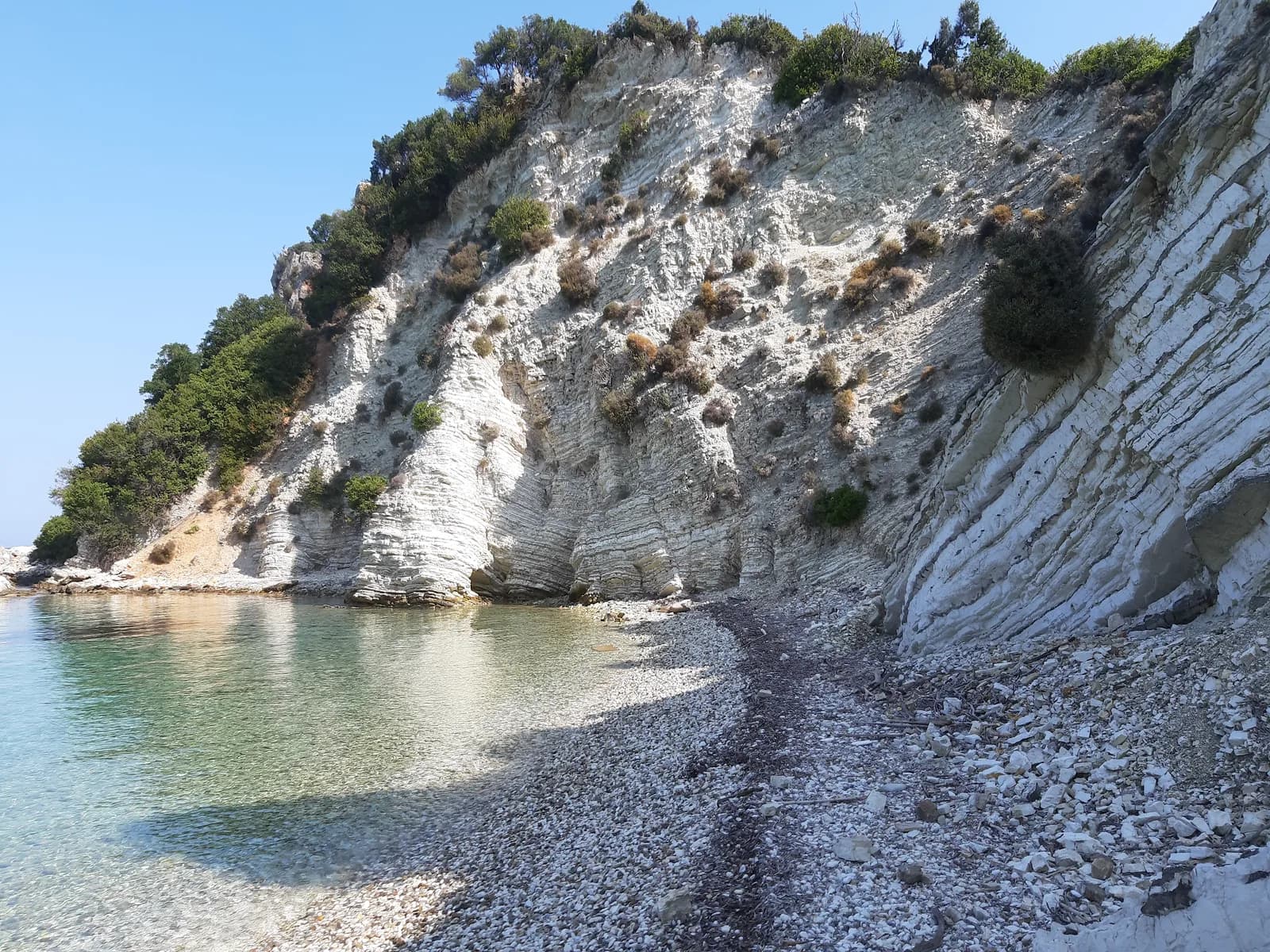 Clear shallow water and a white limestone cliff at the south-east end of Gidaki beach on Ithaca, Greece