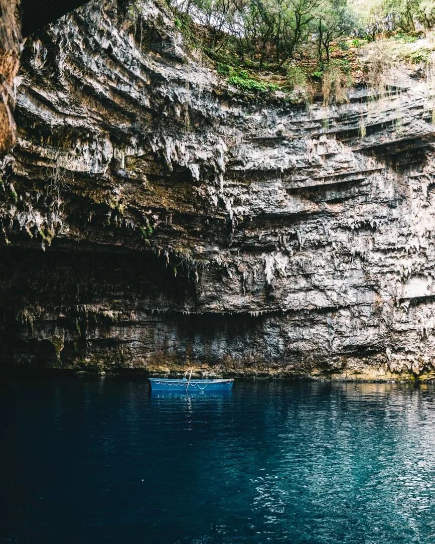 The collapsed roof of the Melissani cave near Sami on Kefalonia, with a blue rowing boat on the underground lake below the limestone walls