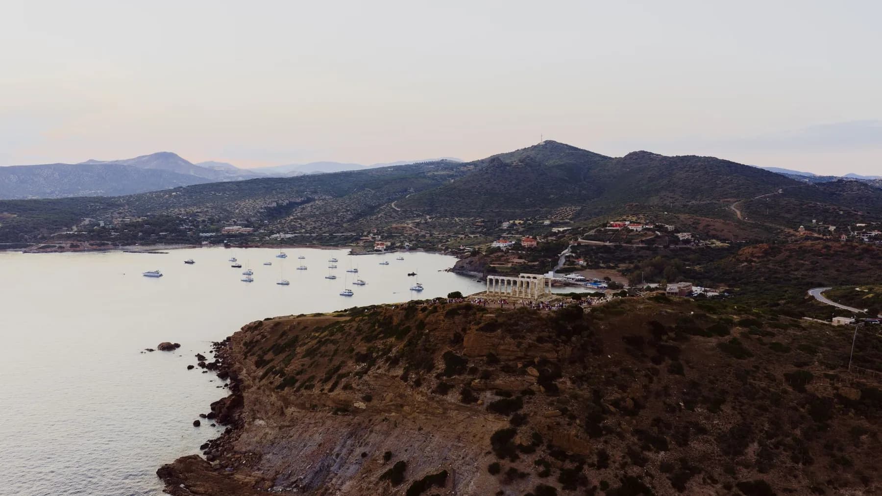 The temple of Poseidon on the headland at Cape Sounion at the southern tip of Attica, with the sheltered bay and its moored yachts behind it