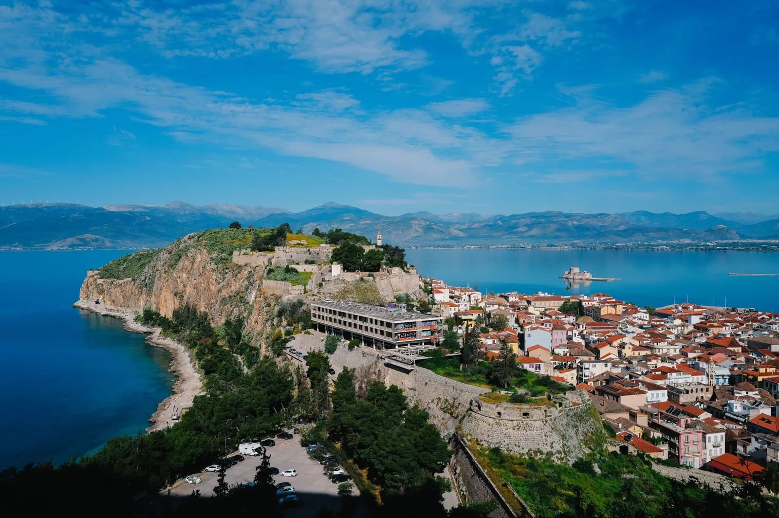 Nafplio in the Peloponnese seen from the Palamidi fortress, the walls of Akronafplia on the headland above the red roofs of the old town, the Bourtzi castle on its islet in the bay and the mountains of the Argolid behind